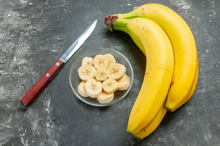 2 bananas, sliced banana in plate and knife | benefits of eating banana on an empty stomach