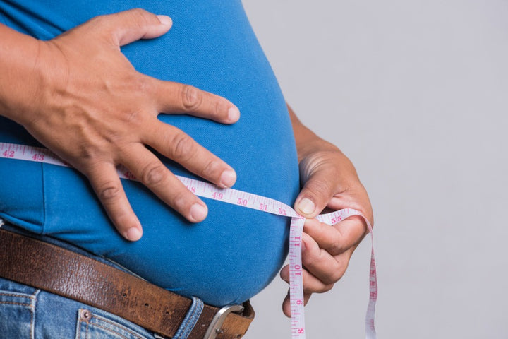 a man measuring his big belly using a measuring tape