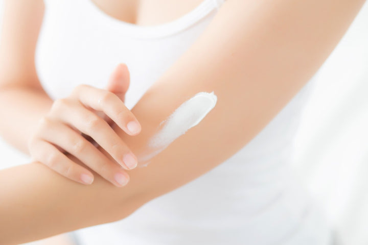 a woman applying body lotion